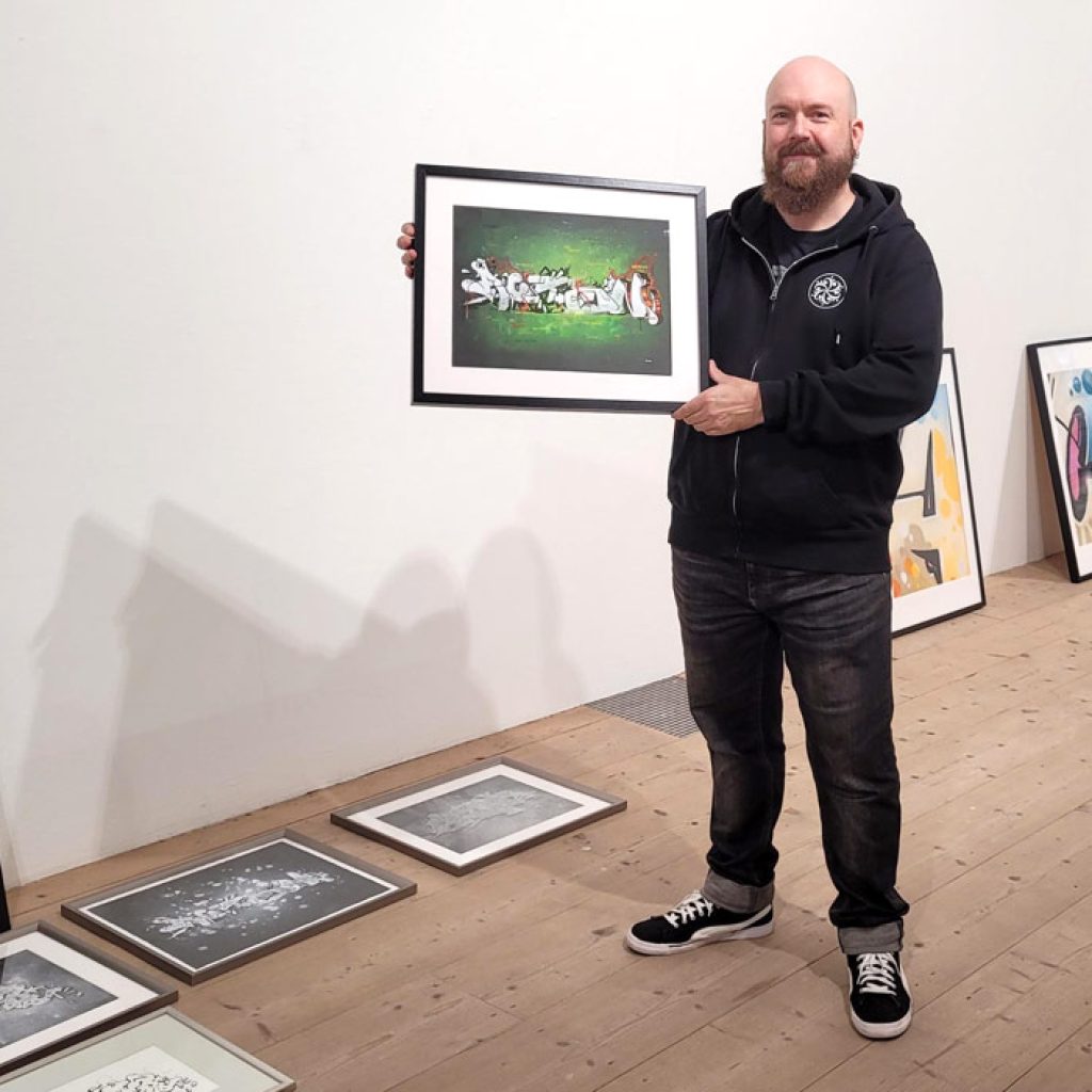 Person holding a framed artwork in his hand.