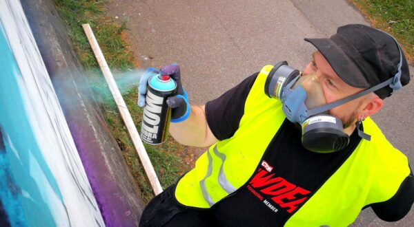 Artist painting a concrete wall with a spraycan.